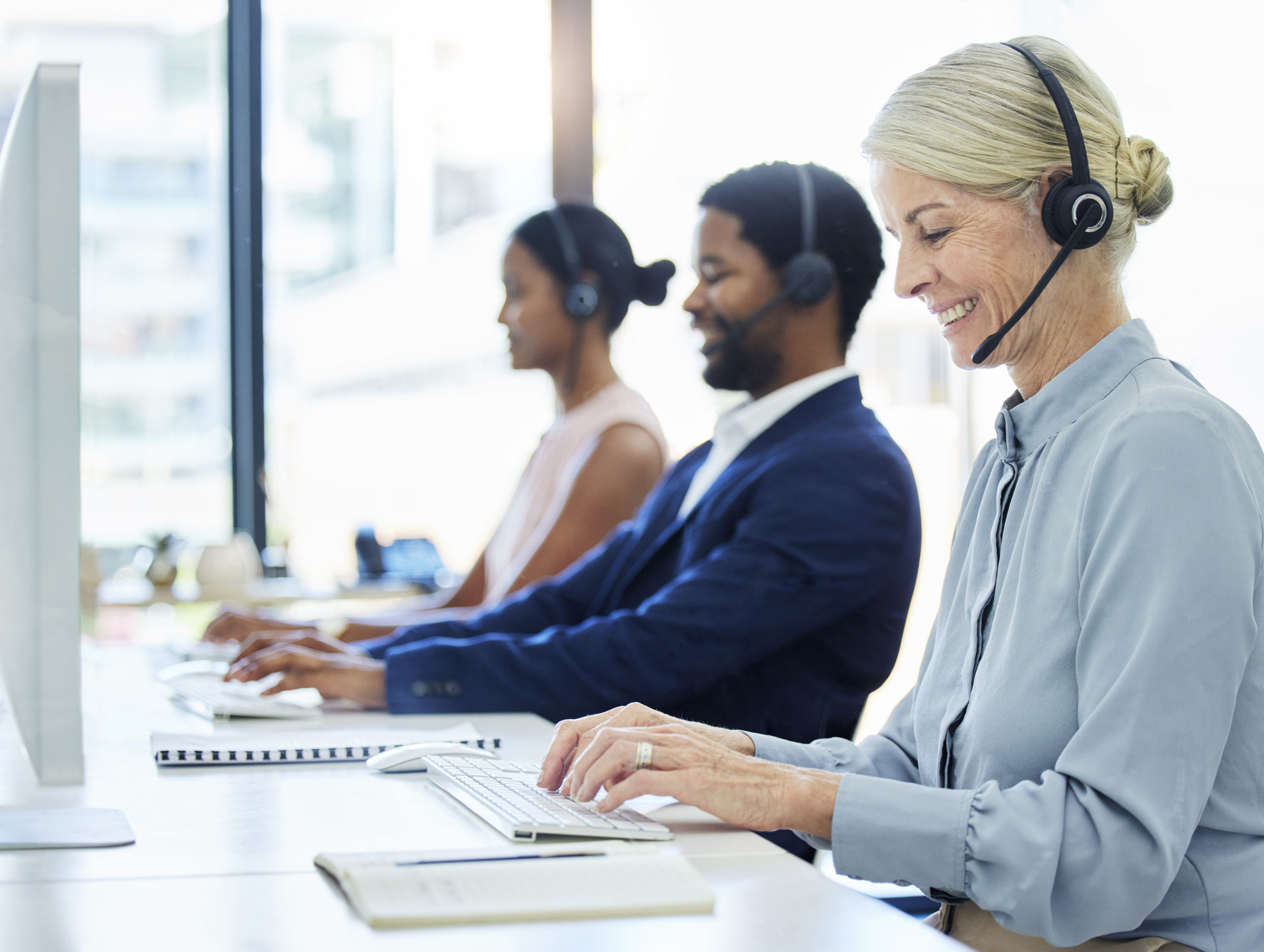 Call center, woman and typing on computer with group in office for online customer support, help or.
